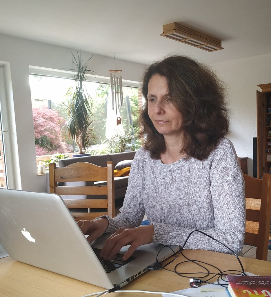 Inge Schumacher sitzt am Computer und schreibt am 5-Minuten Podcast.